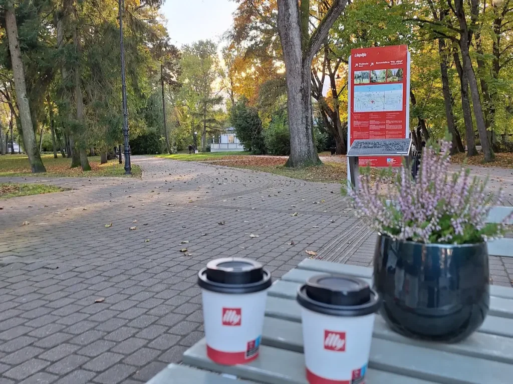 Entrance sign for Jūrmalas parks in Liepāja near a tree-lined path