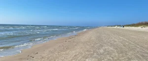 Wide sandy stretch of Liepāja Beach with the Baltic Sea on the left and dunes in the distance
