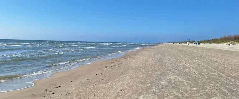 Wide sandy stretch of Liepāja Beach with the Baltic Sea on the left and dunes in the distance