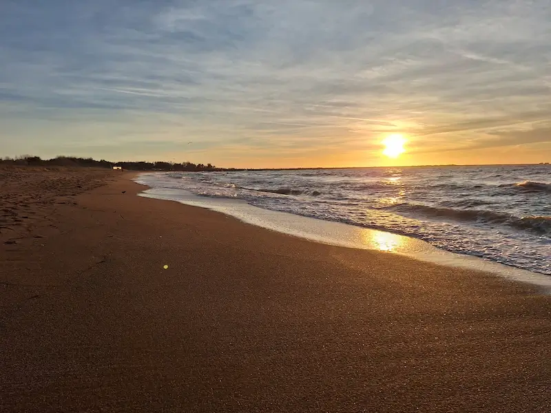 liepaja beach at sunset with the sun reflecting off the baltic sea and golden sands