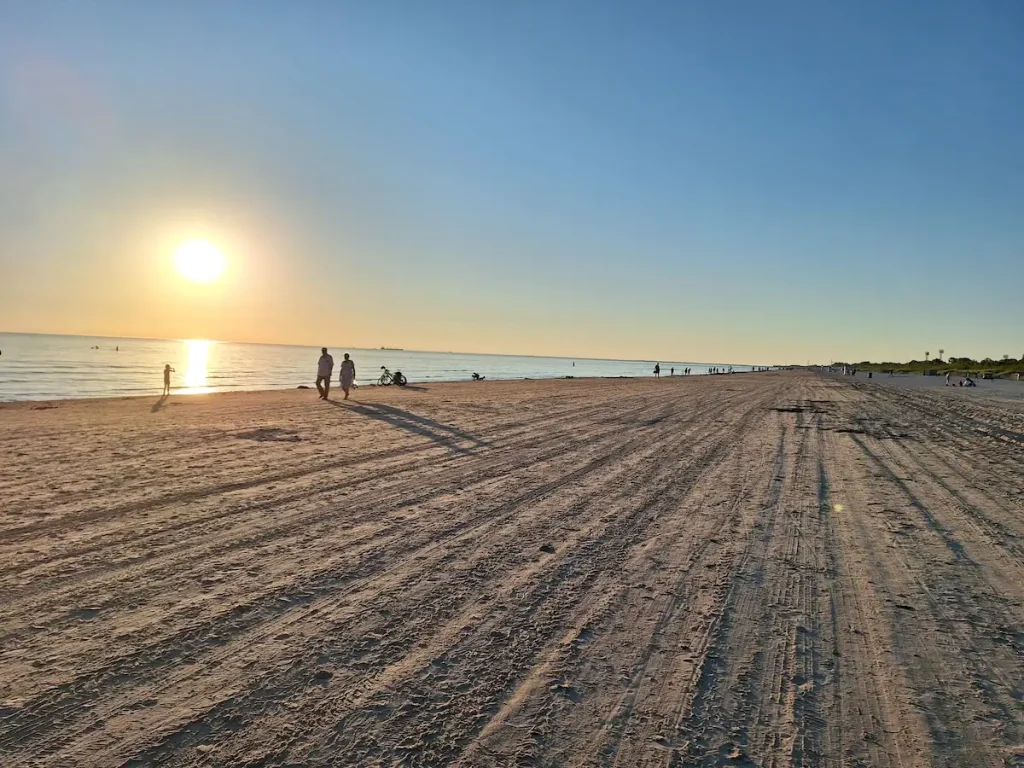 Low sun over Liepāja Beach with wide sand, sea, and a clear Baltic horizon