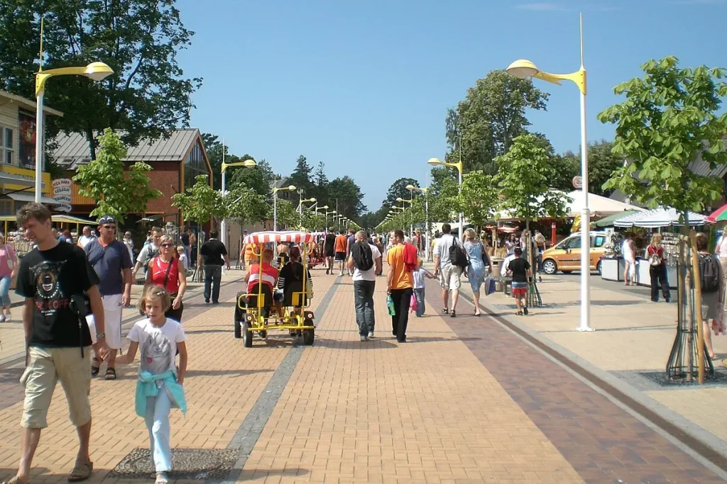 Busy Basanavičiaus gatvė pedestrian street in Palanga, with summer crowds, cafés and pedal carts near the beach.